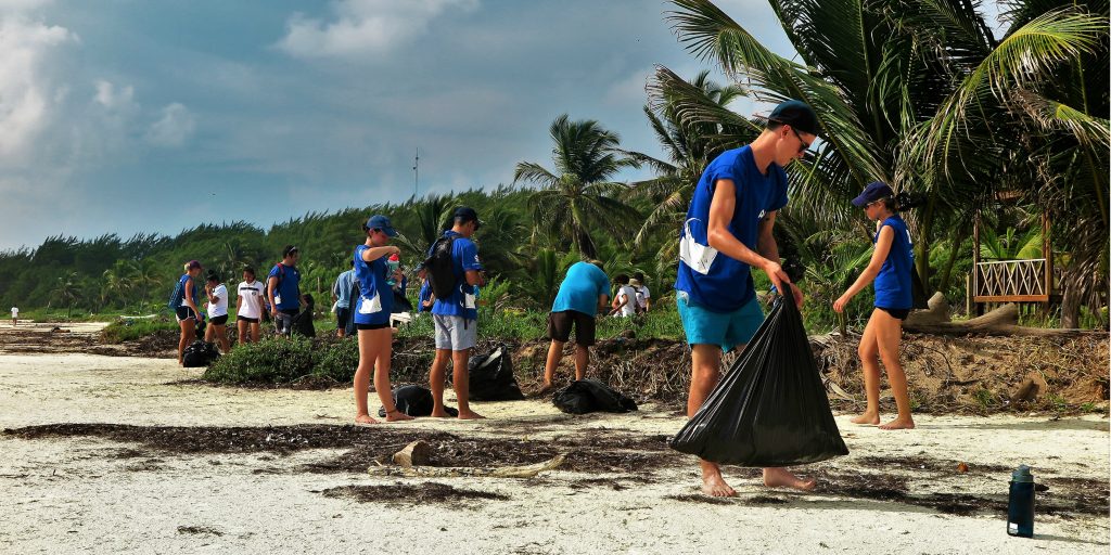 A large group of GVI volunteers collecting litter during a beach clean up.