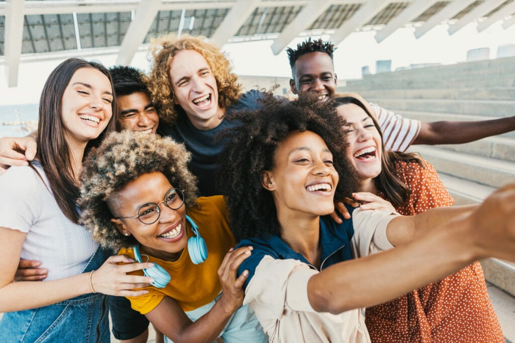 International group of young multicultural people taking selfie portrait with smart phone outdoors - Best trendy friends having fun together on holidays - Friendship lifestyle and unity concept - Focus on afro woman