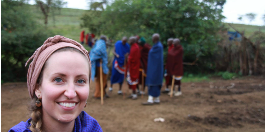 A volunteer standing in front of a group of men in traditional wear in Africa.