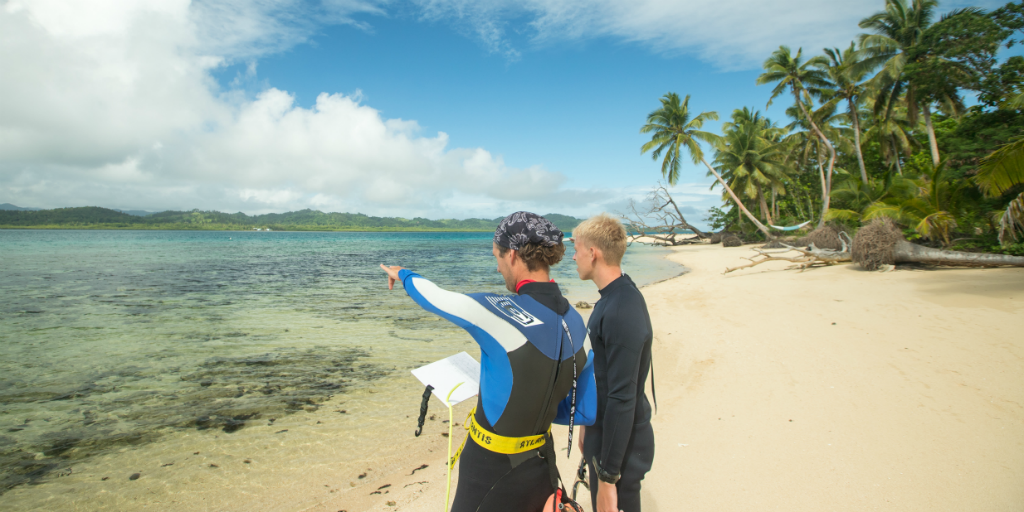 One volunteer pointing out towards the ocean while speaking to another volunteer.