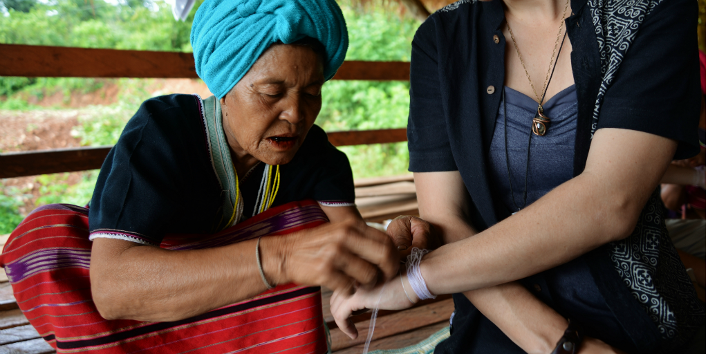 White string being tied around a woman's arm, a traditional Karen practise.
