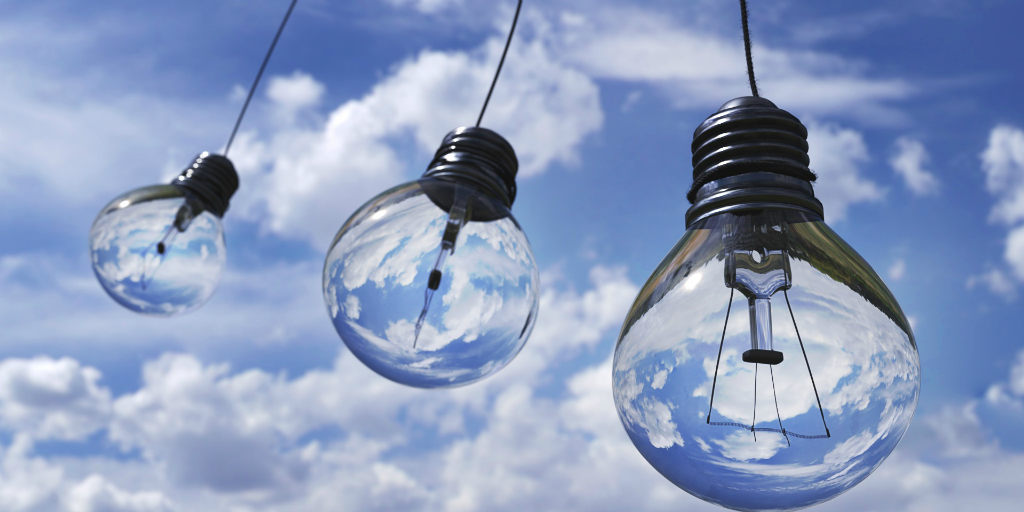 Three light bulbs hanging outside on a cable.