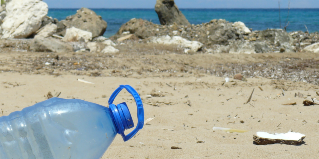 A plastic bottle lying on a beach.