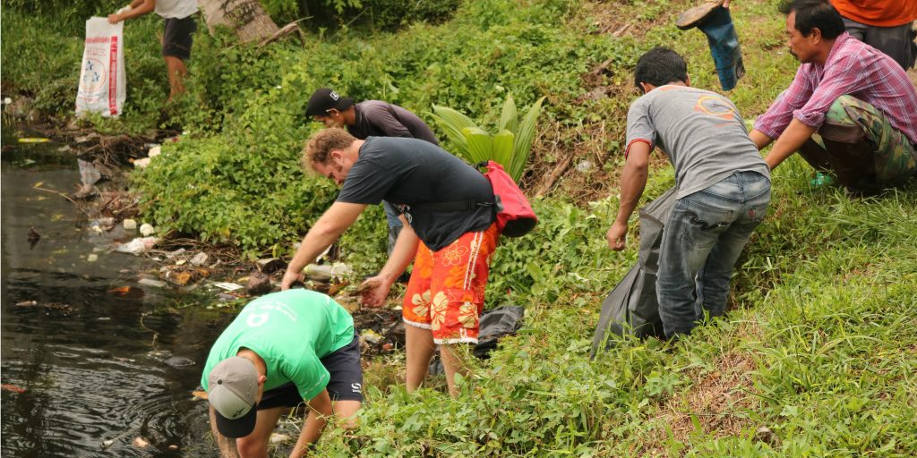 GVI volunteers partner with the local community to clean up plastic pollution along the water's edge in Phang Nga, Thailand.