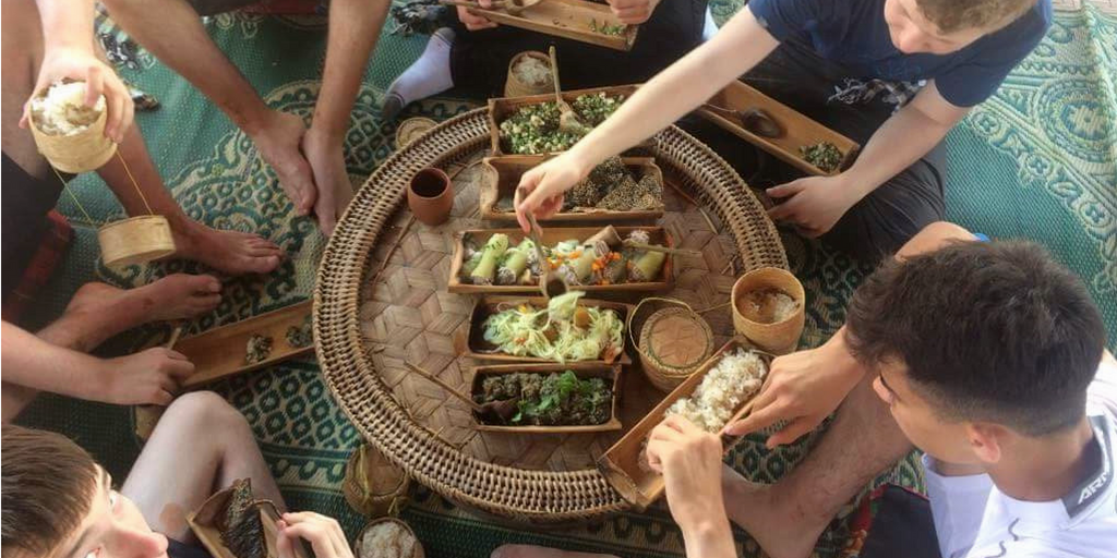 Students sitting around eating local Laos food