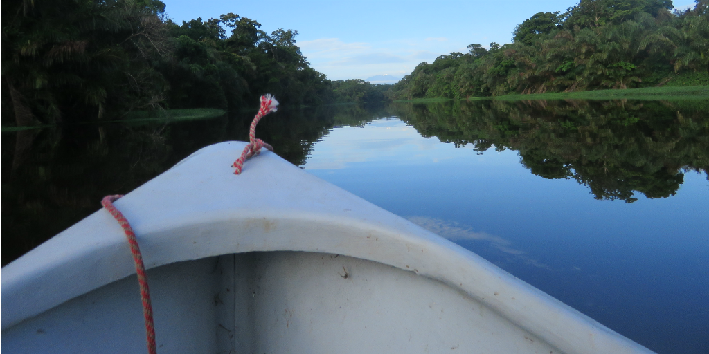 A boat travelling down a river framed by the Costa Rican Rainforest on either side.