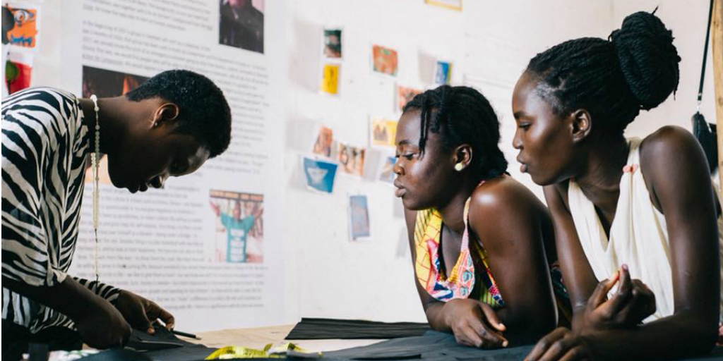 Two Ghanaian women watching a third woman doing a demonstration.