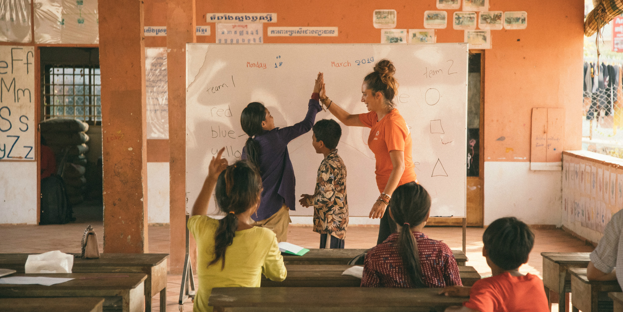 A GVI communications intern celebrates with a learner while on a gap year travel program in Cambodia.