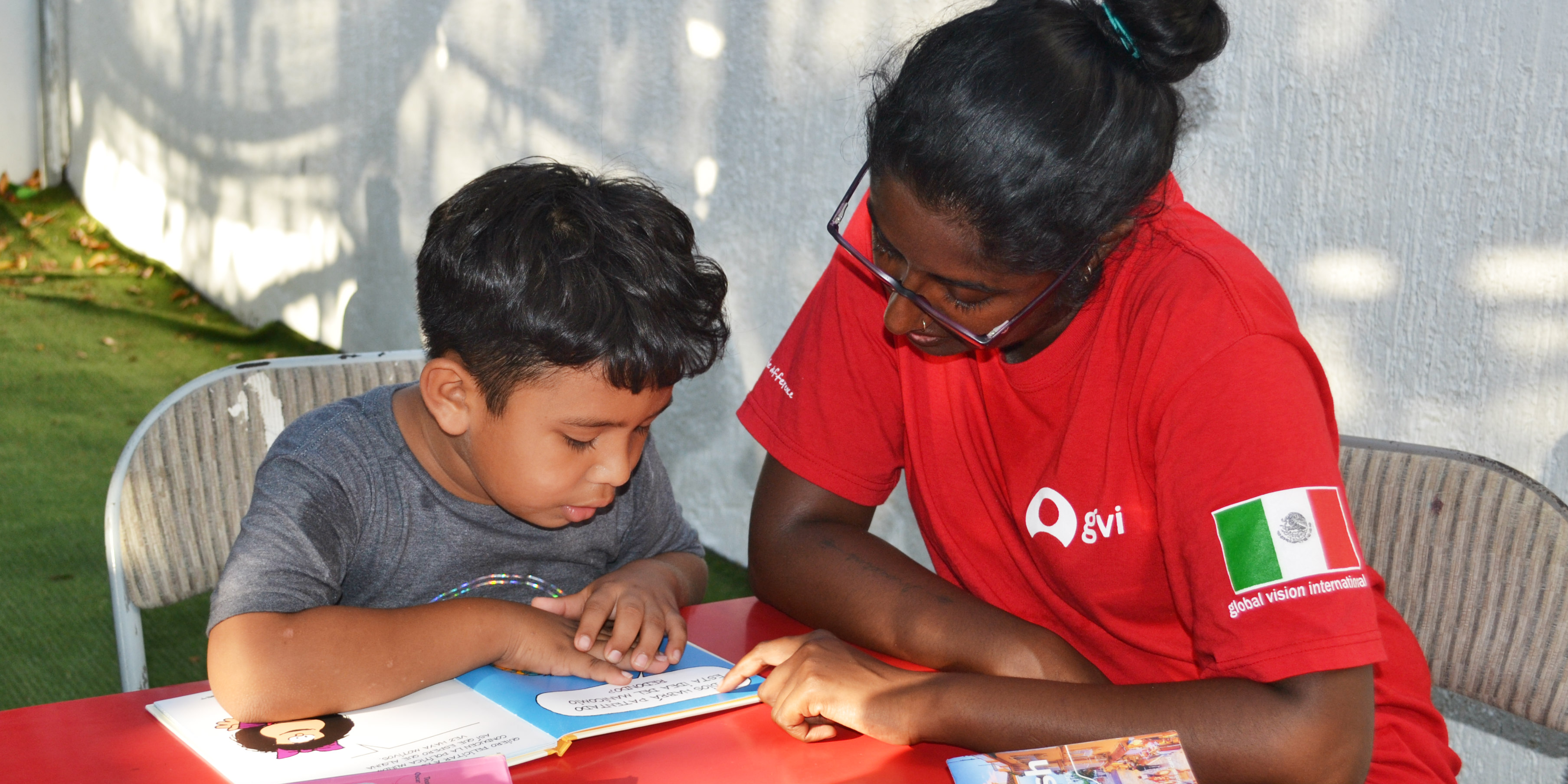 A GVI participant works with a child on their reading, while volunteering in Mexico.