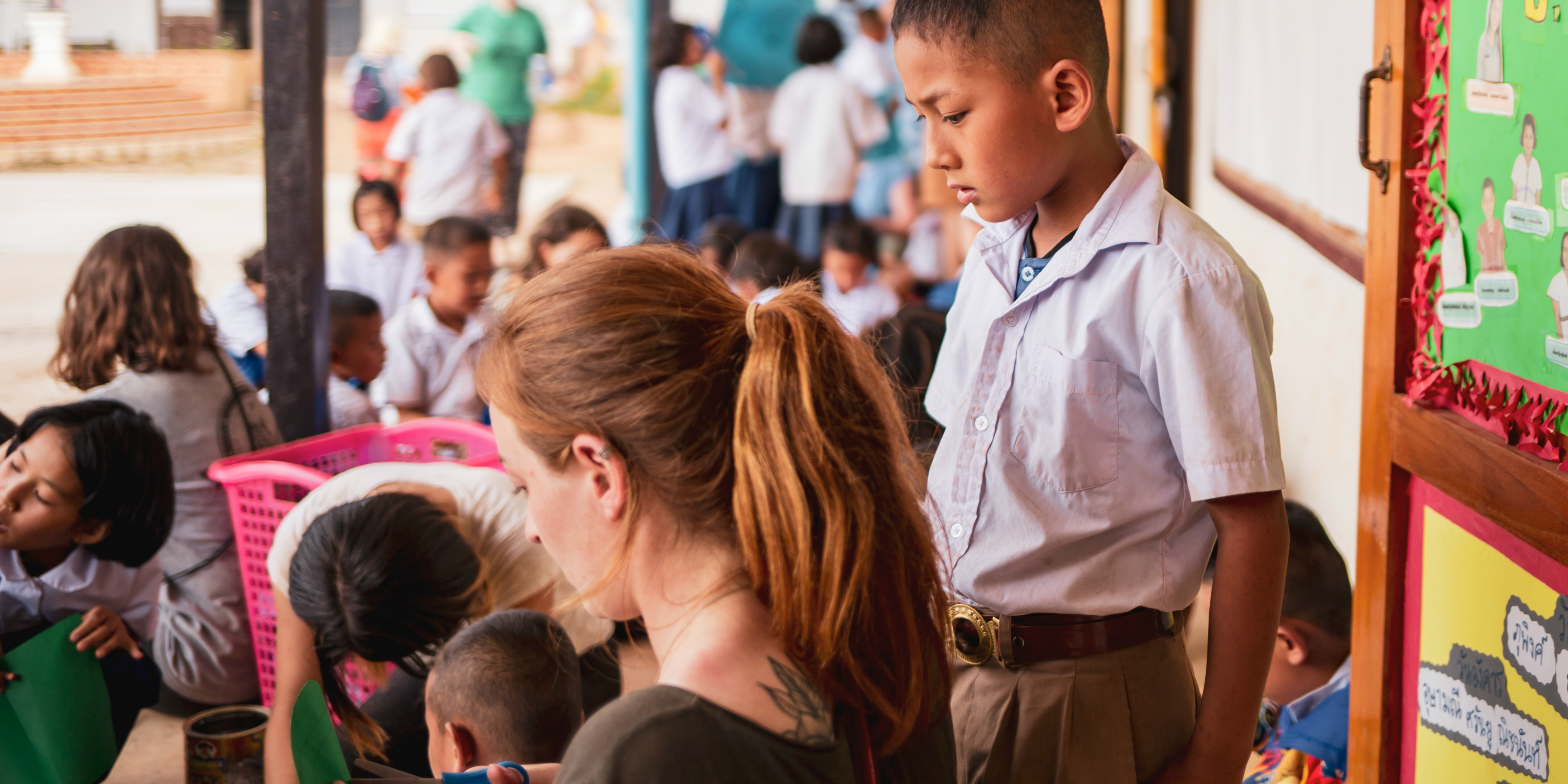 A GVI intern helps a student with their cutting while working to gain a TEFL certification in Thailand.