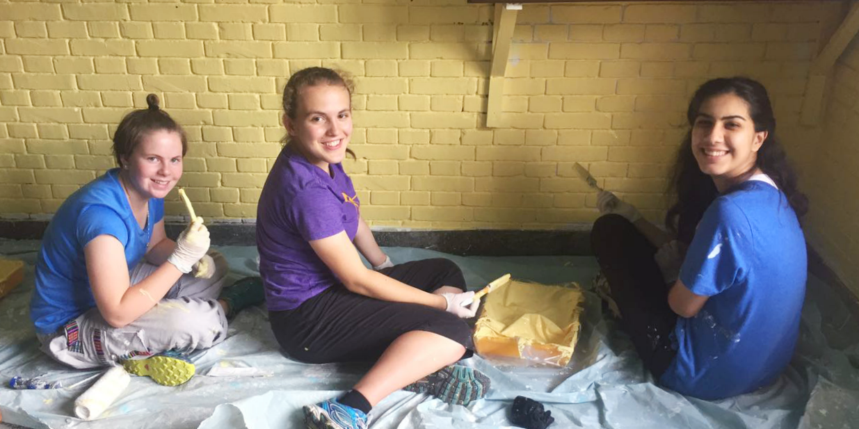Teen volunteers paint a classroom while on a school trips abroad.