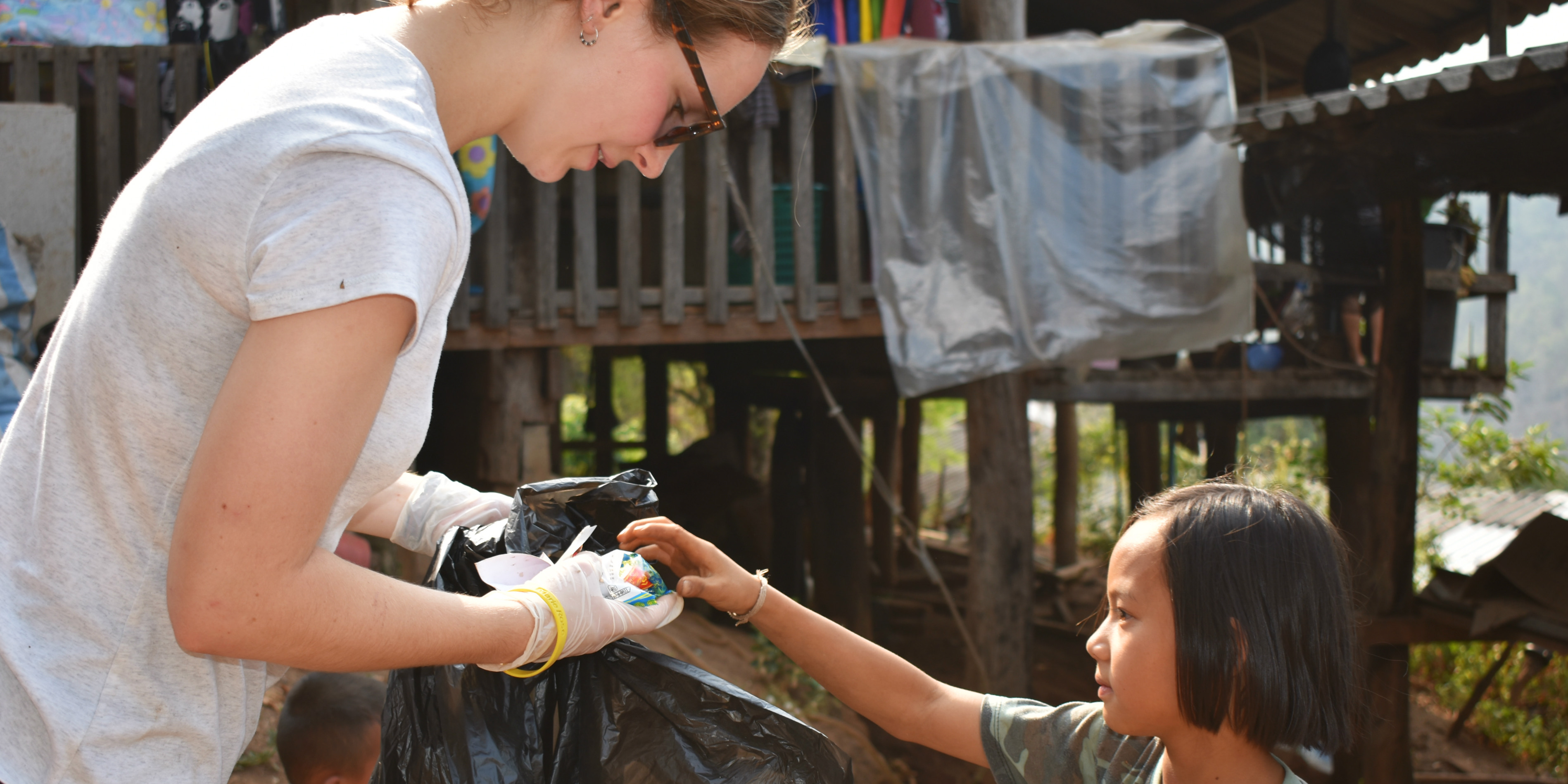 A GVI participant collects plastic waste in Chiang Mai, Thailand, with the help of a young girl. In between working to collect behavioral data on elephants in Thailand, participants work on environmental education initiatives. 