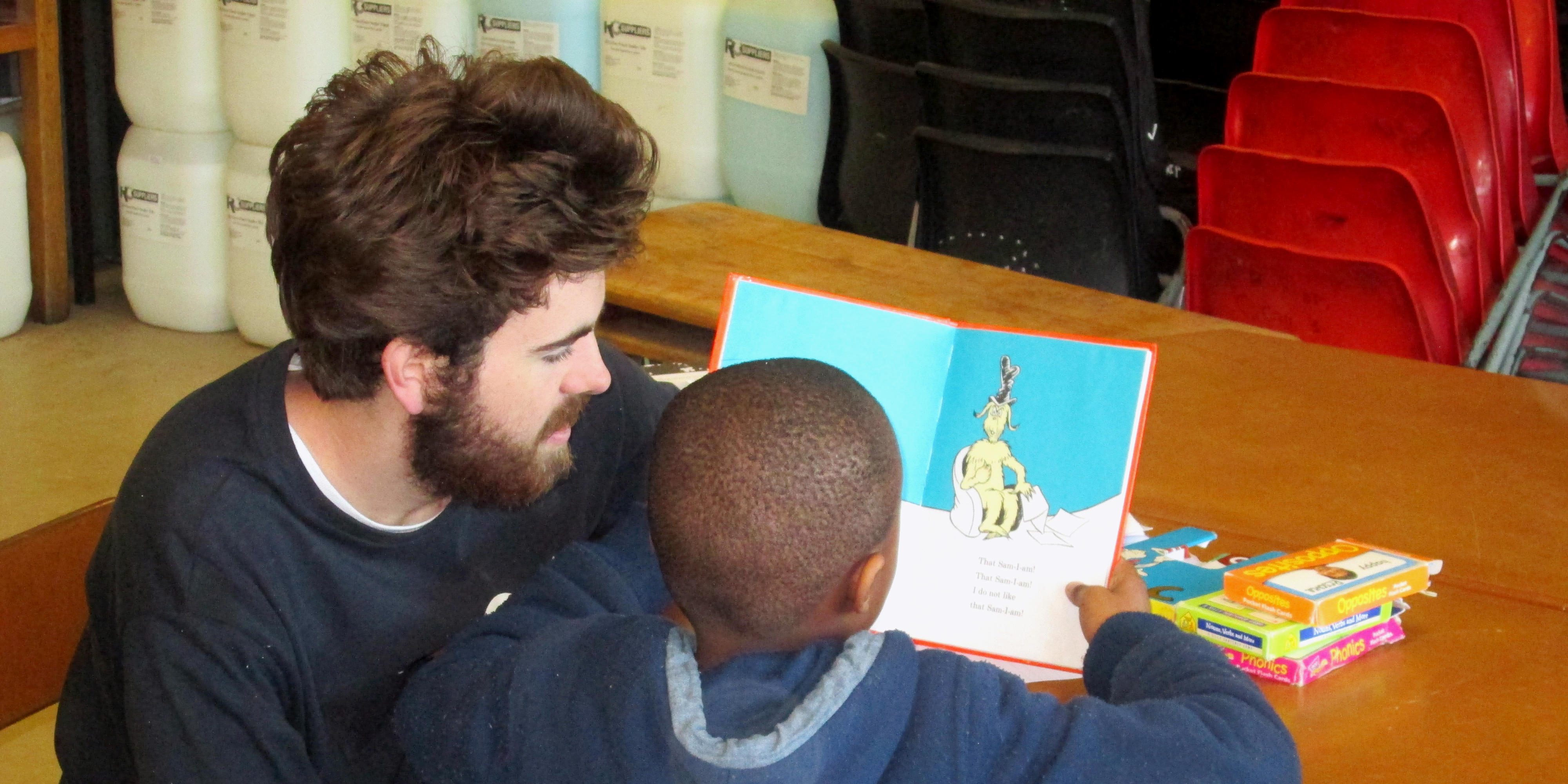 A GVI participant helps a learner with their reading while teaching English abroad.