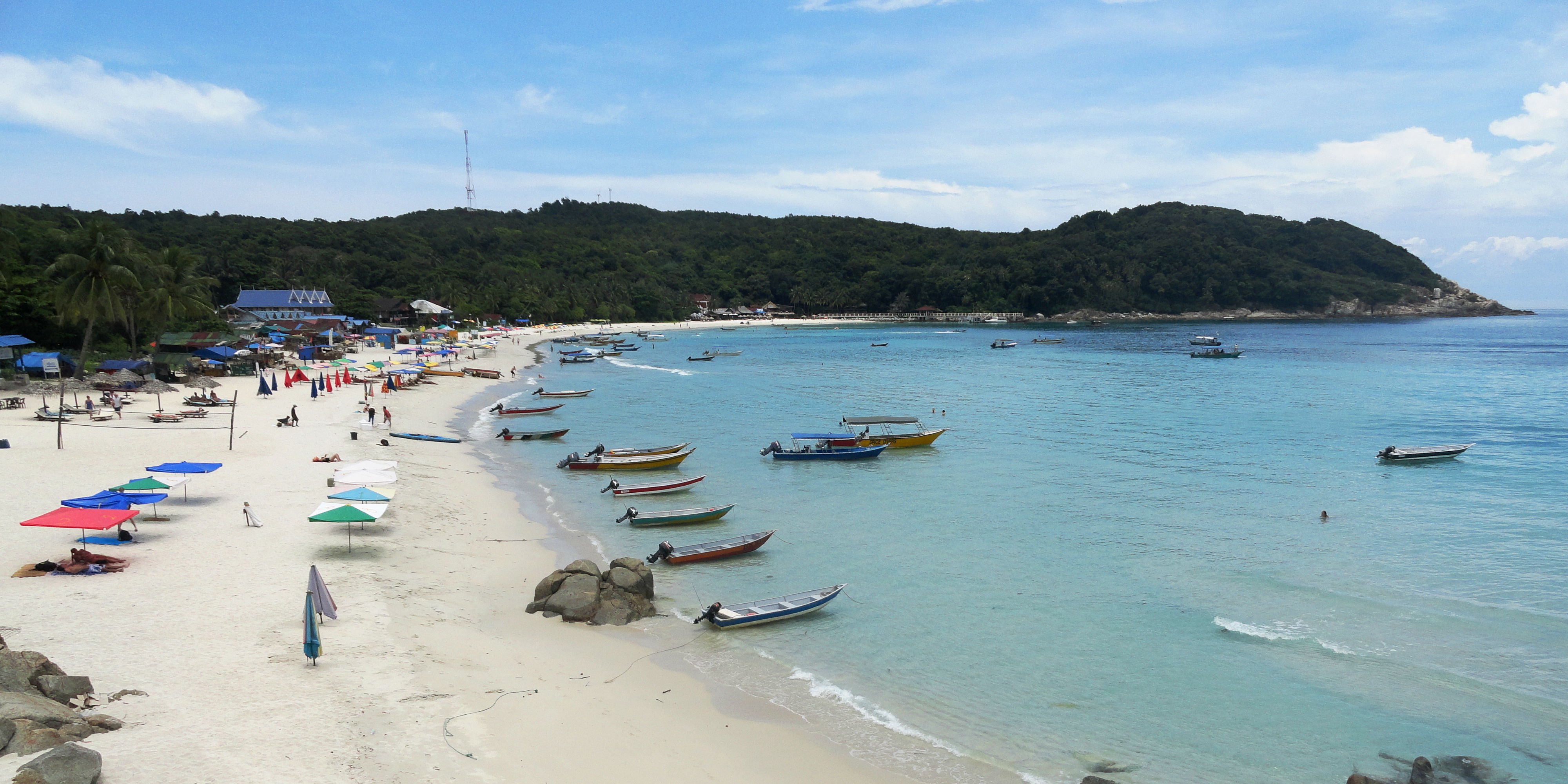 A shot of a beach on the Perhentian Islands shows colourful fishing boats and ebach umbrellas. By promoting sustainable tourism, scenes like this will remain untarnished.
