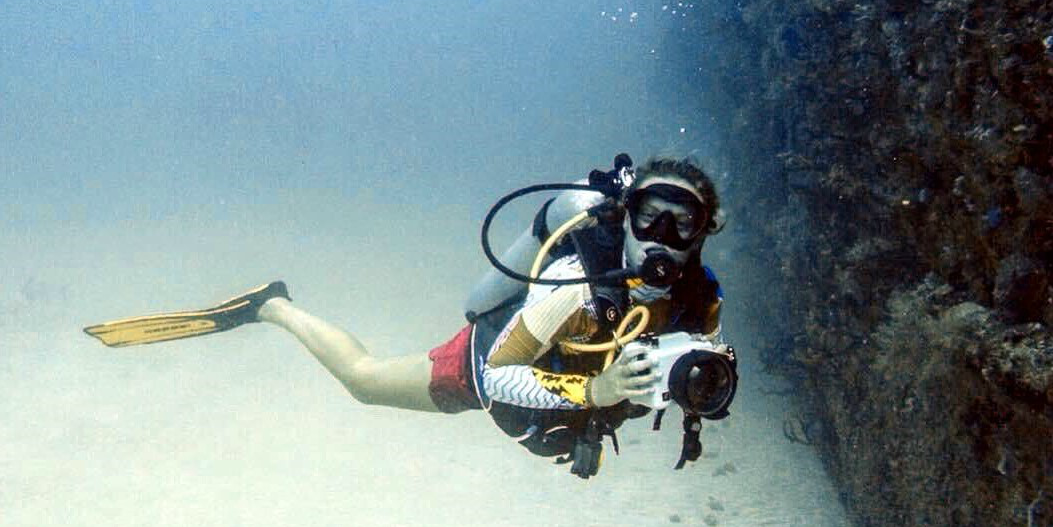 A GVI participant photographs an underwater shipwreck while logging dives for their PADI dive courses.