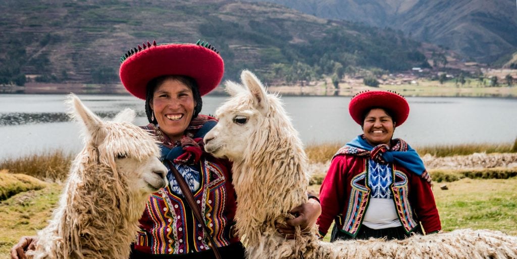 Two women in Cusco pose, while dressed in Andean-styled clothing. Cusco is one the places where you'll have opportunities to see quechua culture in Peru.