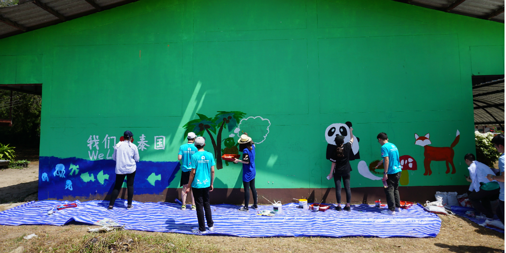 Members of a volunteer group abroad with GVI paint a mural on a wall in Thailand