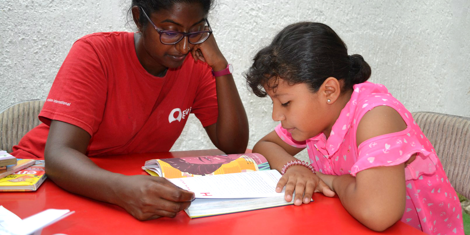 A GVI teacher helps a learner with their reading while on a volunteering with children program.