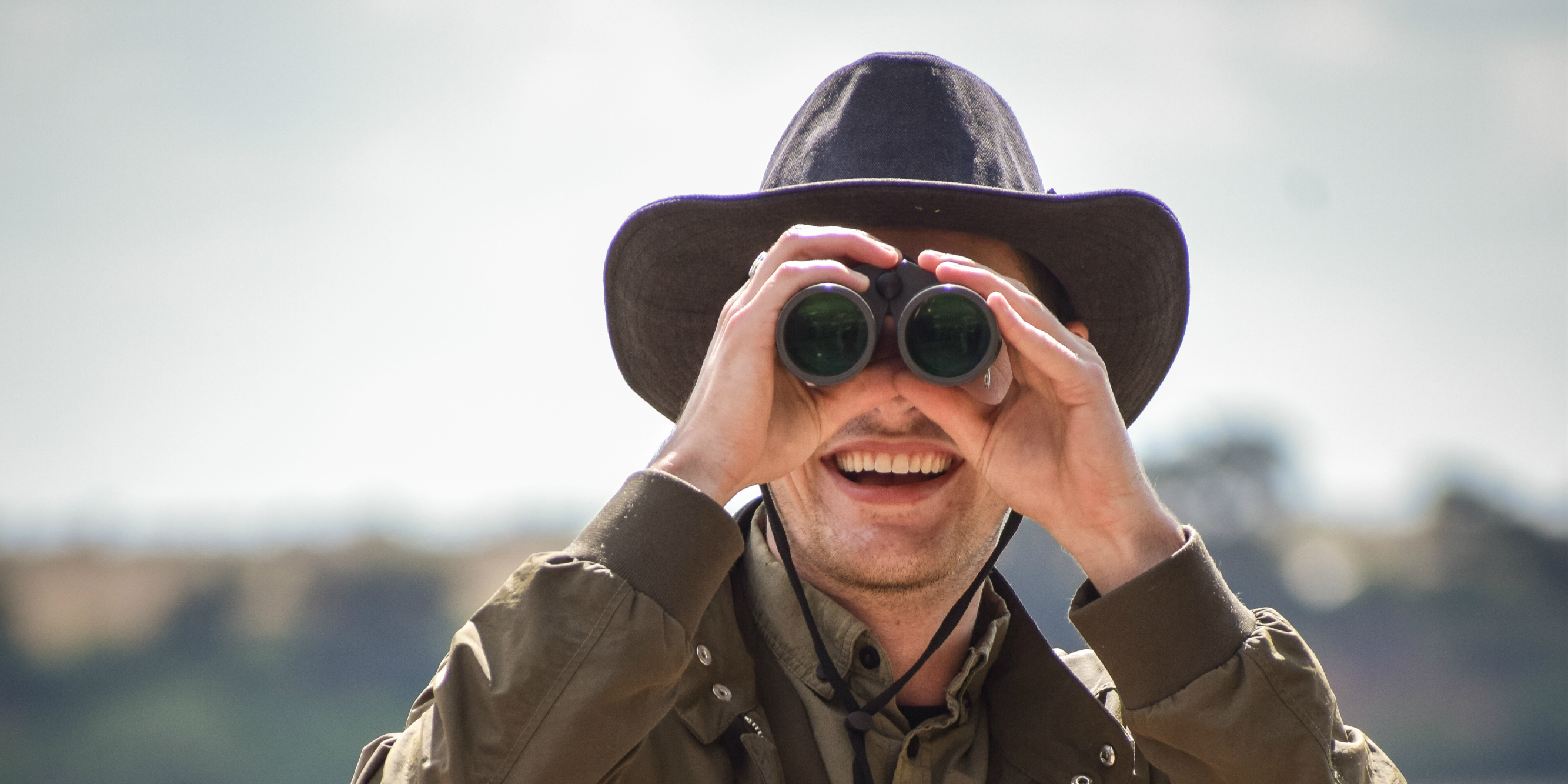 A wildlifer conservation participant looks through binoculars.