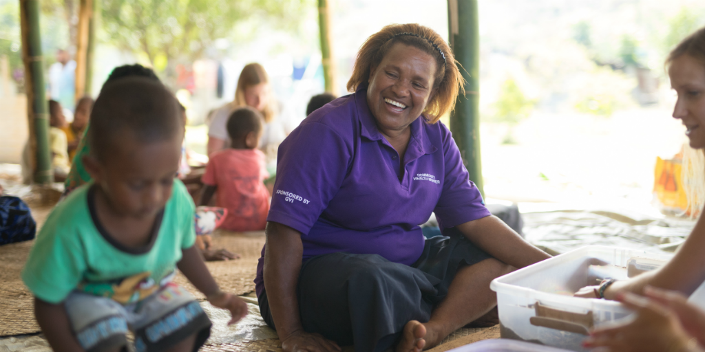Happy local mother watching her child do an activity with a GVI volunteer