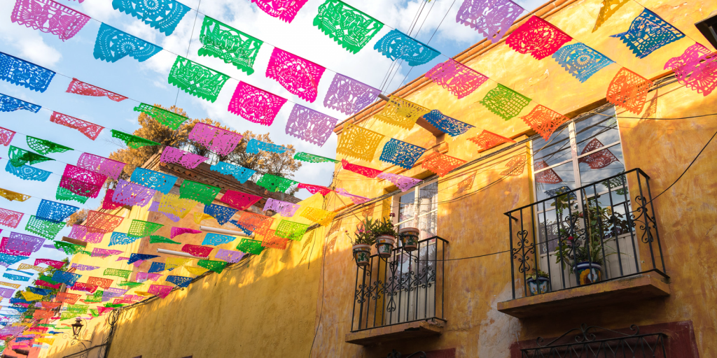 Flags flying from houses in a street in Mexico