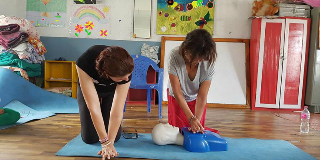Volunteer teaching a local woman to do CPR