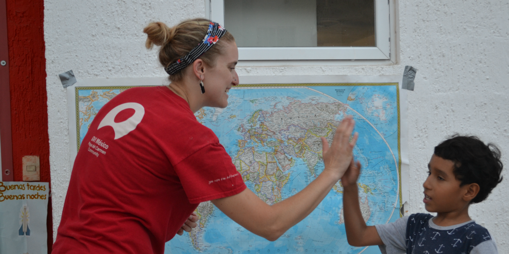 A volunteer congratulating a Mexican child in a class