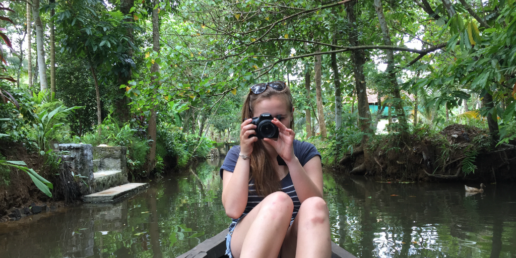 A traveller sitting at the edge of a boat taking a picture