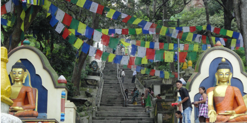 Stairs with religious statues on either side and flags hanging overhead