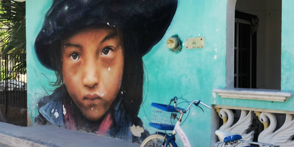 A mural of a Mexican girl on the wall of a home in Cancun with.