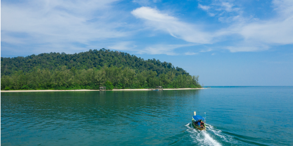 A boat being steered toward an island in Thailand