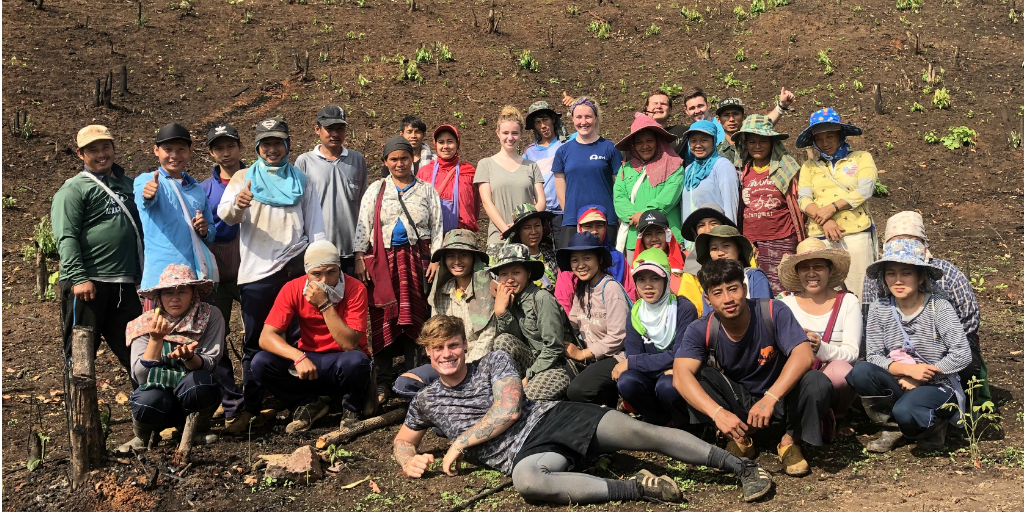 A group of volunteers with local people on a hillside.