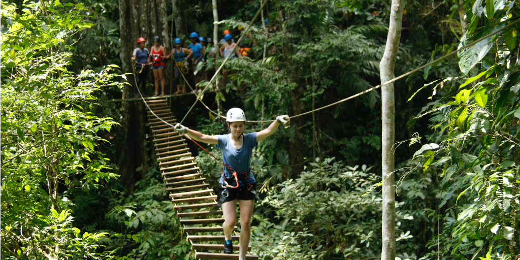 A volunteer wearing a harness and walking across a rope bridge in the jungle in Costa Rica.