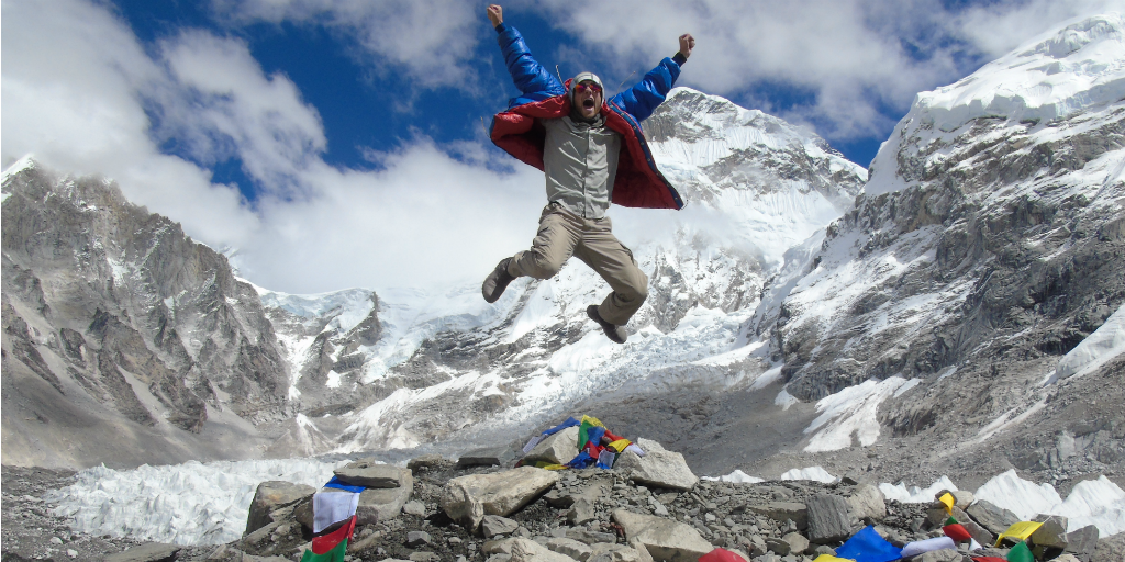 A hiker celebrating his success at reaching Everest base camp.