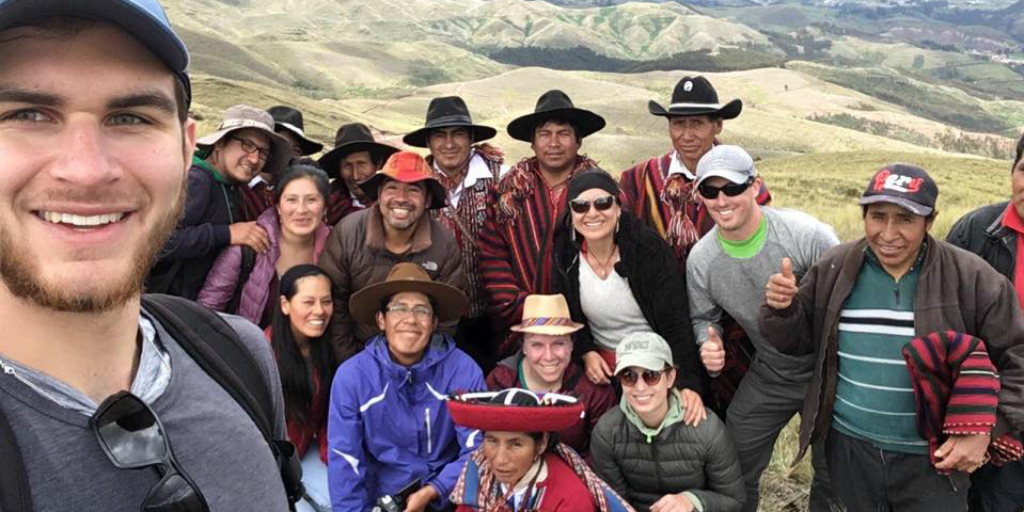 Volunteers posing for a photo with local people with a mountain range in the background.