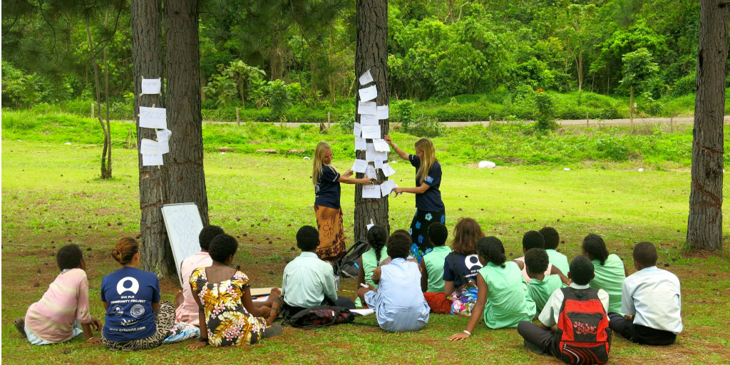 Two volunteers teaching a class outdoors.