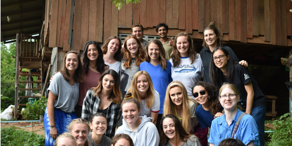 Volunteers posing for a group photo outside of a cabin.