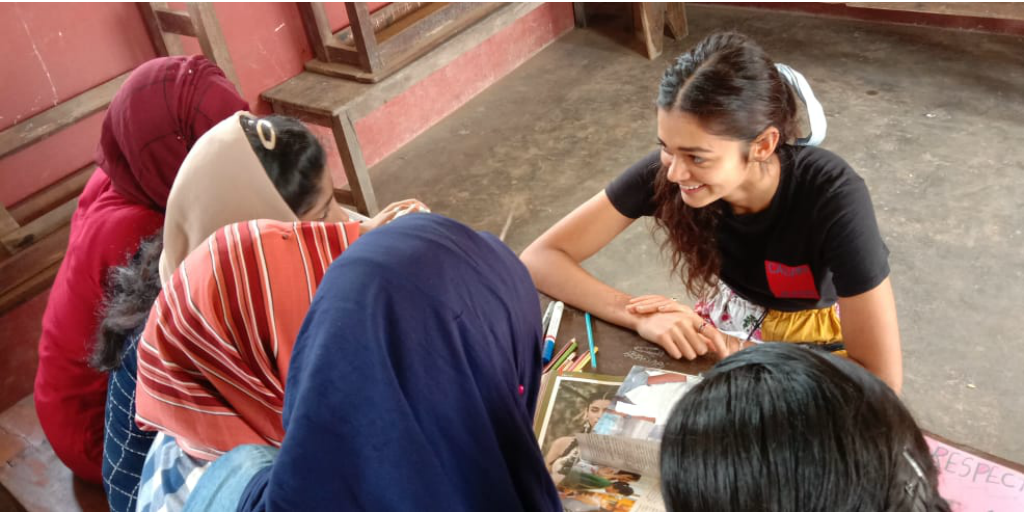 A volunteer sitting at a table with local women in Kerala, India.