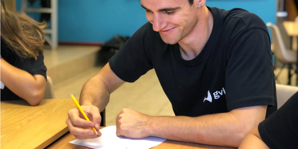 A volunteer sitting at a desk and writing on paper with a pencil.