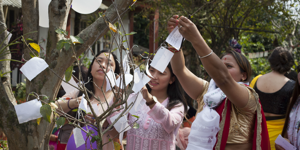 Nepalese women hanging decorations in a tree.
