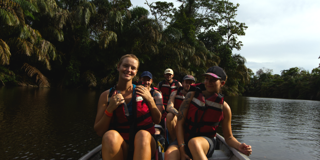 Volunteers wearing life-jackets and sitting in a row boat on a river.