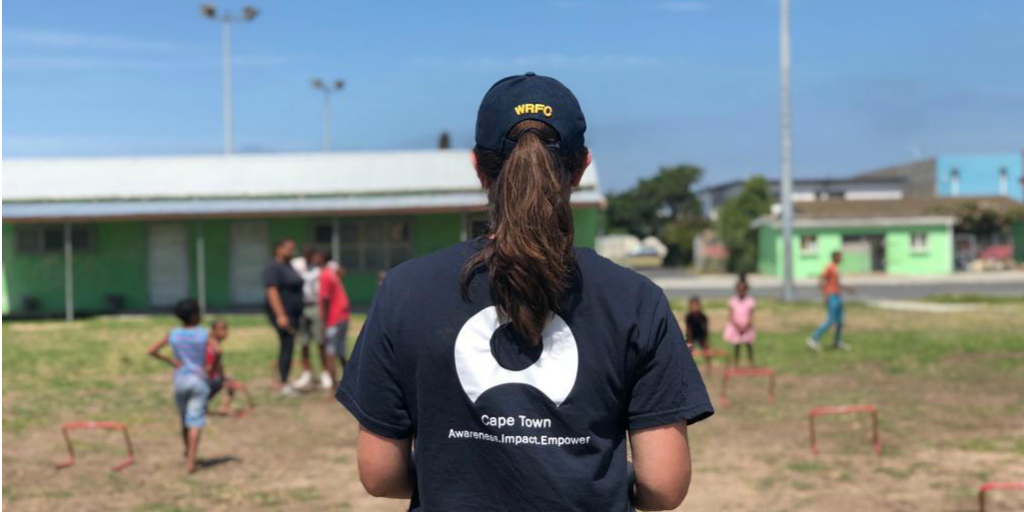 A volunteer supervising a class of children playing outside in Cape Town.