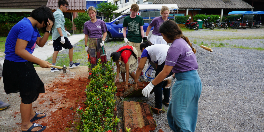 Teen volunteers working on community development garden installments in Thailand