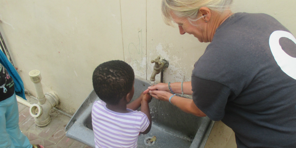 a volunteer teaches children the importance of washing your hands regularly