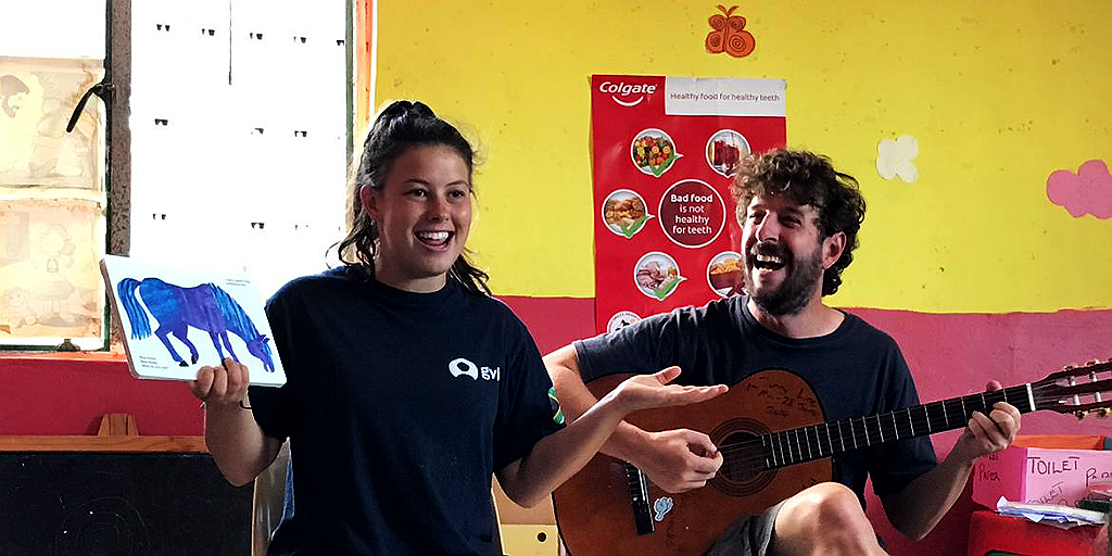 two volunteers lead a song and story time session while contributing to charity work abroad