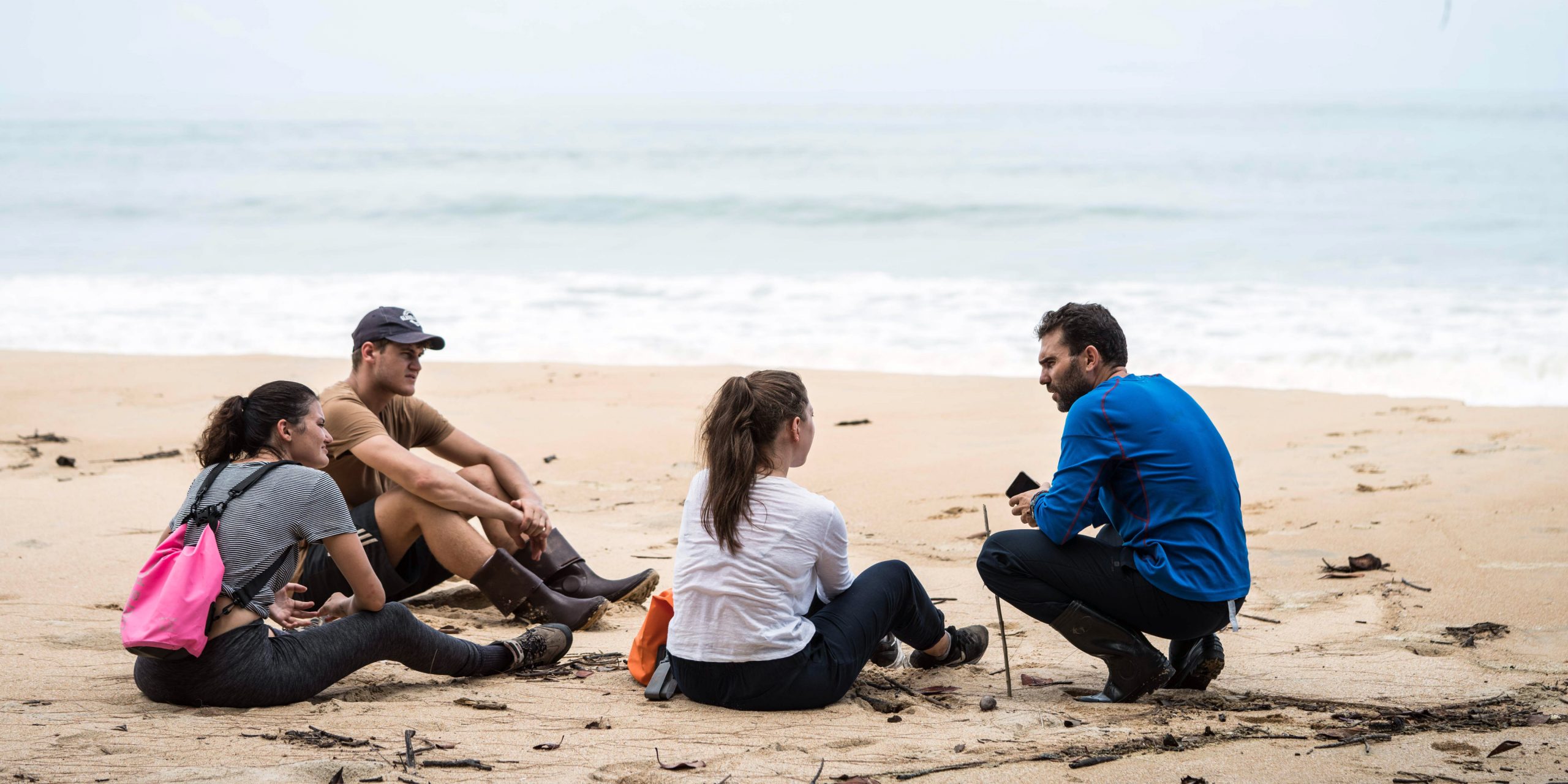 A group of teenage volunteers are briefed on their project on the beach