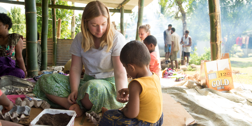 A GVI volunteers gives the child a seed to plant, to create a meaningful experience during her time abroad. 