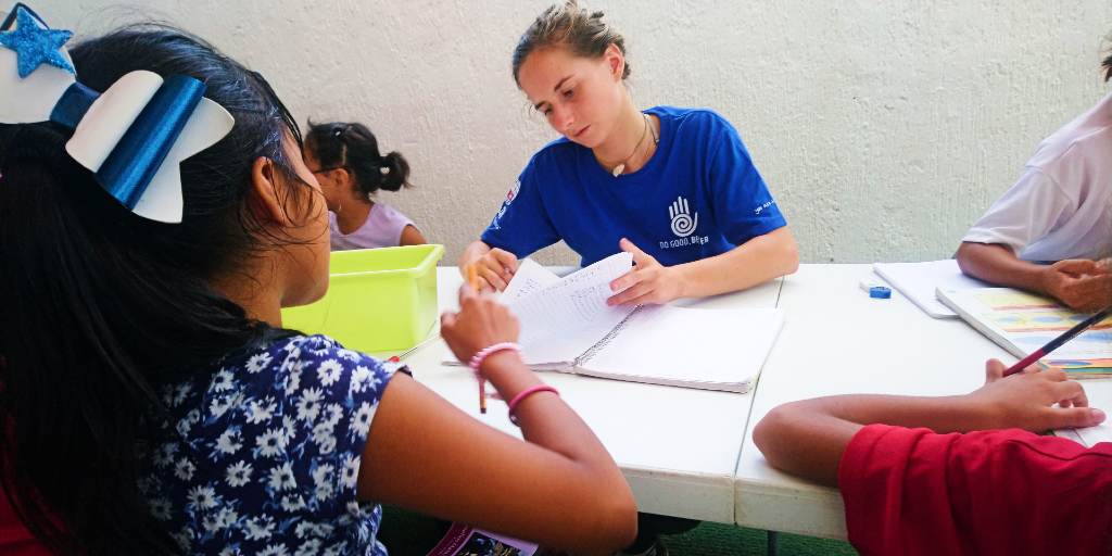 A lady helps a girl with her homework during a summer language immersion program. 