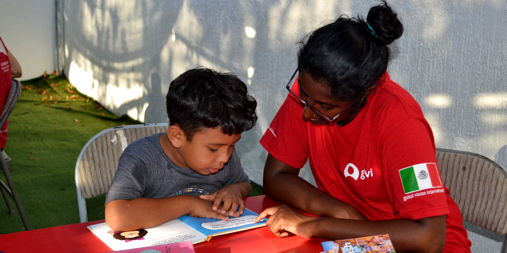 A lady helps a child read a Spanish book during a language immersion program.