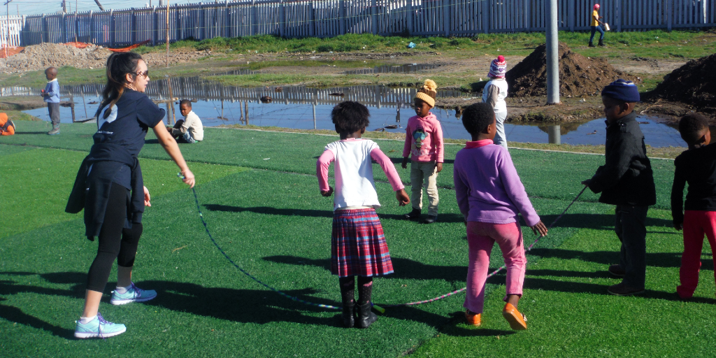 The GVI volunteer plays jump rope with the children. 